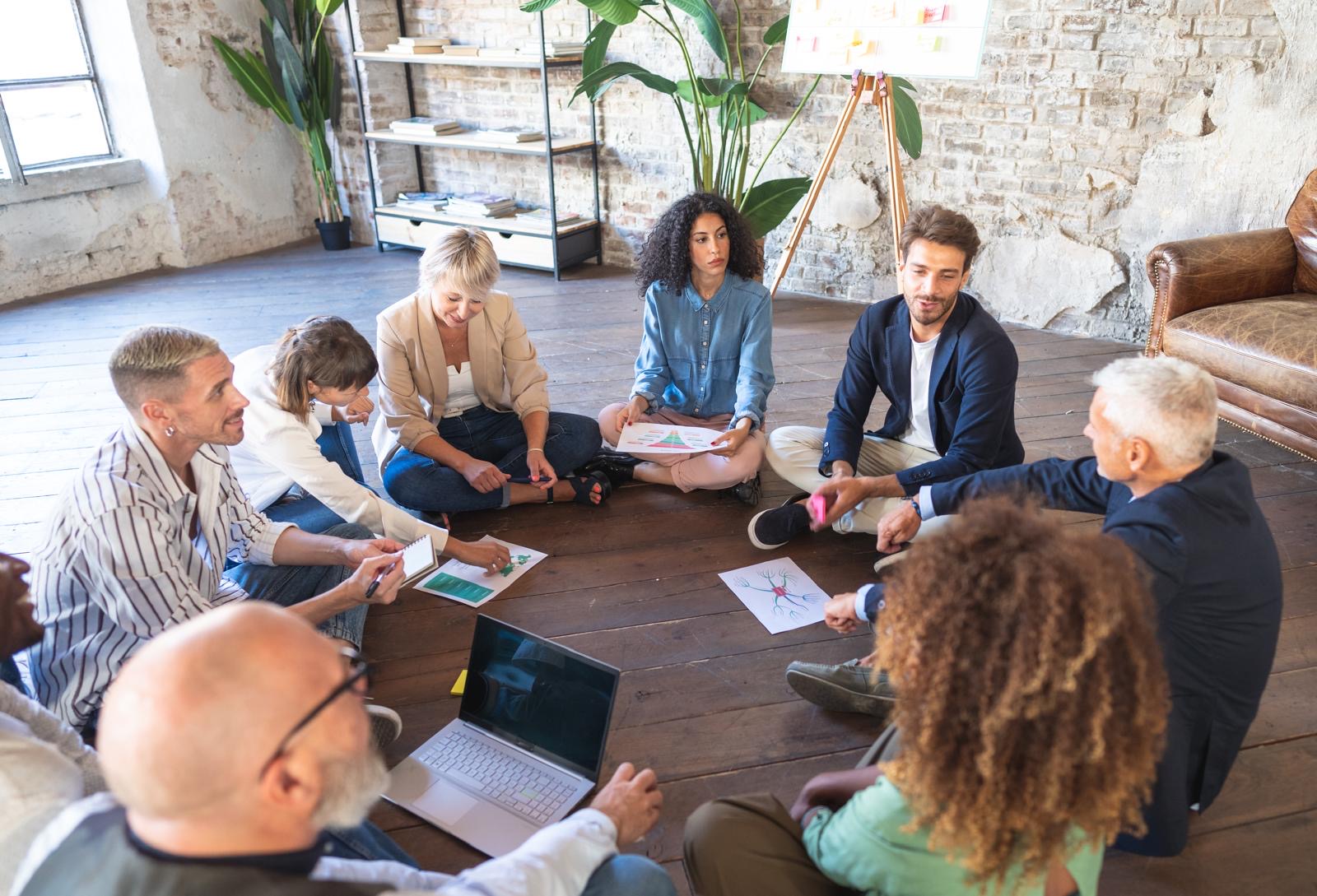 Team coaching session with diverse professionals in a collaborative discussion circle, building communication and resilience.